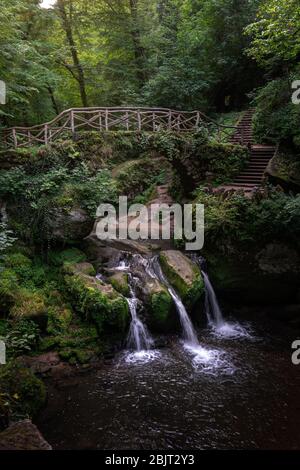 Forêt mystique filmée avec pont sur des cascades en cascade au Luxembourg - les trois petites cascades connues sous le nom de Schiessentuempel à Mullerthal, Luxembour Banque D'Images