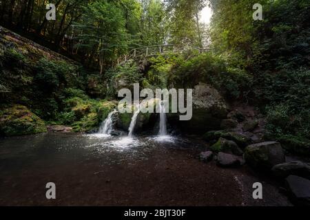 Forêt mystique filmée avec pont sur des cascades en cascade au Luxembourg - les trois petites cascades connues sous le nom de Schiessentuempel à Mullerthal, Luxembour Banque D'Images