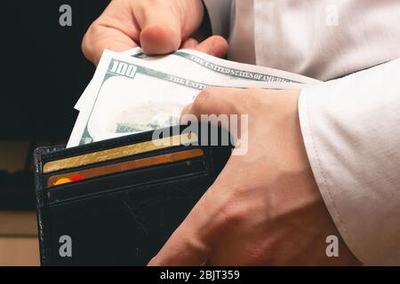 l'homme sort du portefeuille de factures de cent dollars dans une chemise blanche au bureau Banque D'Images