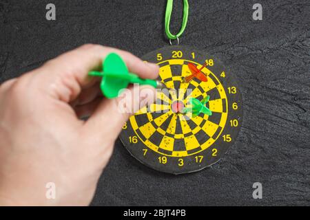 la main jette une découpe dans un tableau de fléchettes sur le béton noir Banque D'Images