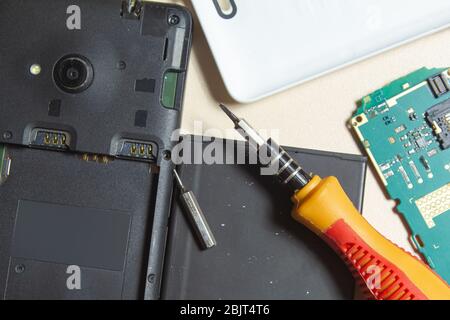 tournevis de batterie de la carte de circuit imprimé de réparation du téléphone sur fond clair Banque D'Images