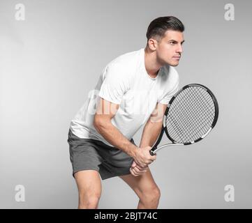 Portrait de beau homme jouant au tennis sur fond gris Banque D'Images