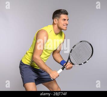 Portrait de beau homme jouant au tennis sur fond gris Banque D'Images