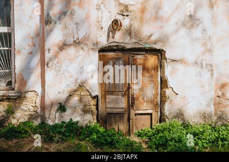 Ancienne porte en bois sur un mur délaqué et s'effondrant. Banque D'Images