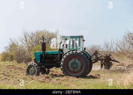 Un tracteur bleu ancien charrue un champ et cultive le sol. Agriculture. Banque D'Images