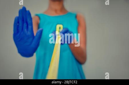 Photo conceptuelle de l'éloignement social pendant la crise du coronavirus. Focalisation sélective sur la bande jaune. Et les gants. Arrière-plan flou Banque D'Images