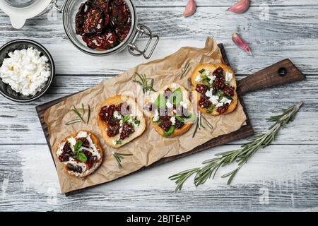 Savoureuses bruschettas avec tomates séchées sur planche en bois, vue sur le dessus Banque D'Images