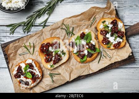 Savoureuses bruschettas avec tomates séchées sur planche en bois, vue sur le dessus Banque D'Images