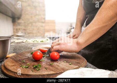 Chef préparant la garniture pour la pizza à la table dans la cuisine du restaurant Banque D'Images