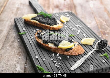 Tranches de pain au caviar noir et beurre sur carton en bois Banque D'Images