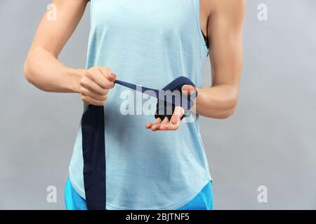 Boxer femme appliquant des poignets enveloppés sur fond gris Banque D'Images