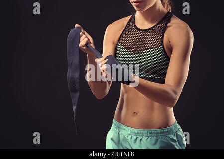 Boxer femme appliquant des poignets enveloppés sur fond noir Banque D'Images