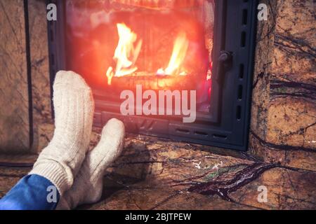 Femme dans des chaussettes chaudes reposant près de la cheminée à la maison Banque D'Images