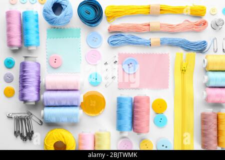 Composition avec fils à coudre et accessoires sur fond blanc, vue de dessus Banque D'Images