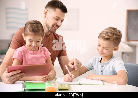 Les petits enfants mignons font leurs devoirs avec leur père Banque D'Images