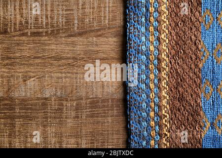 Textile à motifs sur fond en bois. Texture du tissu Banque D'Images