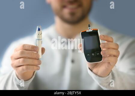 Homme diabétique avec glucometer numérique et stylo lancet, closeup Banque D'Images