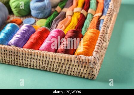 Plateau en osier avec différents types de fils sur fond couleur, gros plan Banque D'Images