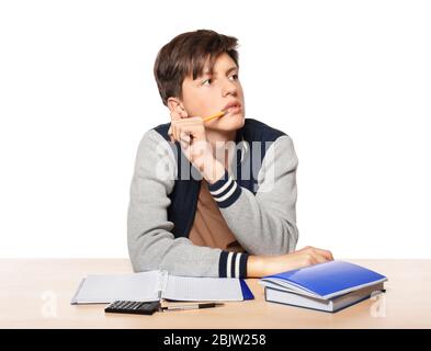 Joli garçon adolescent faisant des devoirs sur fond blanc Banque D'Images