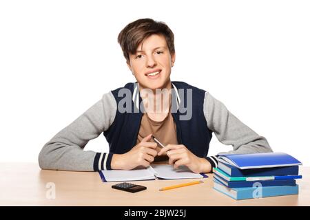 Joli garçon adolescent faisant des devoirs sur fond blanc Banque D'Images