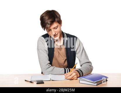 Joli garçon adolescent faisant des devoirs sur fond blanc Banque D'Images