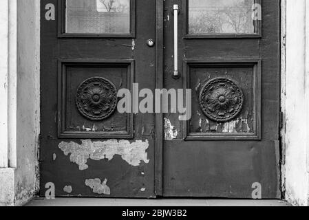 Photo en noir et blanc des éléments architecturaux de la vieille porte avec peinture écaillée et taches. Rosettes sculpturales en cadres carrés de panneaux de portes Banque D'Images