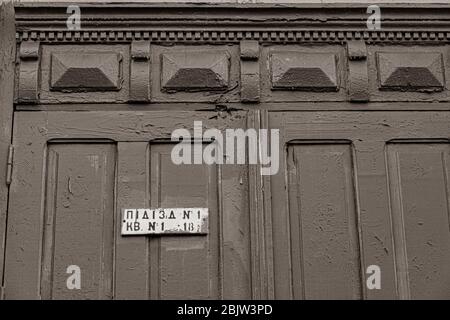 Photo sépia de la décoration de la vieille porte en bois ornée de peinture écaillée et de la plaque signalétique en métal 'Porch' en langue ukrainienne. Cadres et carvi Banque D'Images