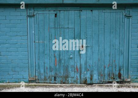 Ancienne porte en bois et mur peint en bleu vert. Planches en bois désalées avec pièces de fond sales pourries. Fond en bois en bois vieilli Grunge avec c Banque D'Images