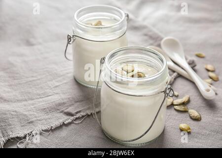 Yaourt avec graines de citrouille en pots sur tissu Banque D'Images