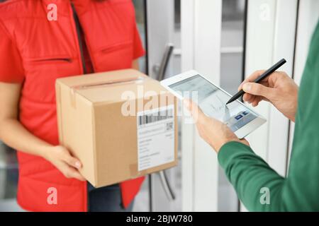 L'homme ajoute la signature après avoir reçu le colis du courrier à l'intérieur Banque D'Images