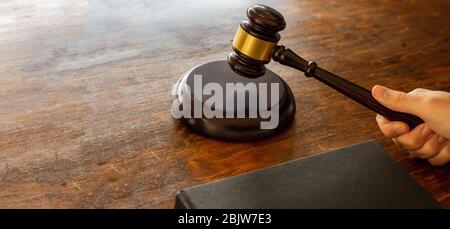 Juge tenant un gavel sur le fond de bureau de palais de justice en bois, bannière. Thème de la loi. Banque D'Images