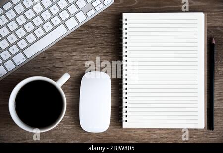 Vue panoramique sur un bureau à domicile avec clavier, café, souris et carnet en spirale avec espace de copie doublé pour les notes Banque D'Images