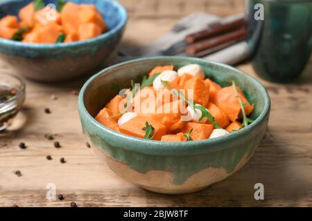 Bol avec délicieuse pomme de terre douce coupée et fromage sur table Banque D'Images