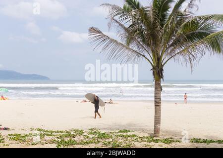 Vietnam Beach - UN surfeur qui marche le long de My Khe Beach à Da Nang au Vietnam, en Asie du Sud-est. Banque D'Images