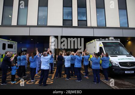 Les infirmières se sont clap alors que leurs collègues regardent d'une fenêtre à l'hôpital universitaire Queen Elizabeth de Glasgow alors qu'ils se joignent aux applaudissements pour saluer les héros locaux au cours du Clap national de jeudi pour que les soignants reconnaissent et soutiennent les travailleurs et les soignants du NHS qui luttent contre la pandémie de coronavirus. Banque D'Images