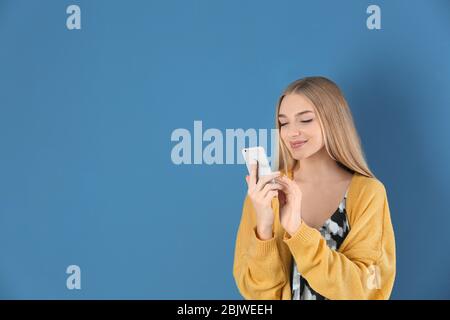 Belle jeune femme avec un téléphone mobile sur un fond de couleur Banque D'Images