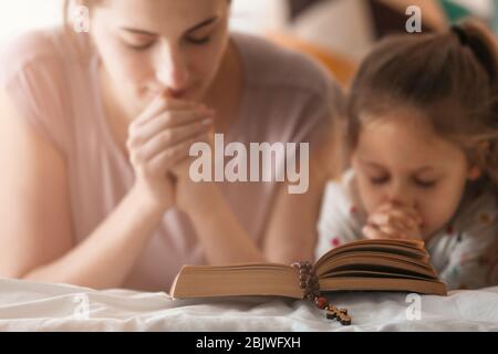 La fille chrétienne religieuse et sa mère priant sur la Bible à l'intérieur Banque D'Images