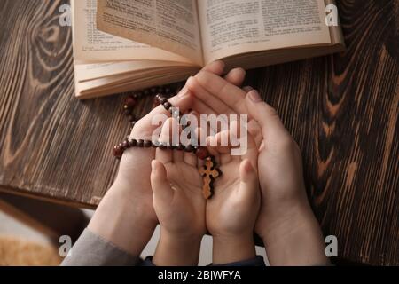 Fille chrétienne religieuse avec sa mère tenant des perles rosaire à la table, closeup Banque D'Images