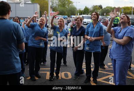 Les infirmières se démènent vers leurs collègues alors qu'elles regardent d'une fenêtre à l'hôpital universitaire Queen Elizabeth de Glasgow alors qu'elles se joignent aux applaudissements pour saluer les héros locaux au cours du Clap national de jeudi pour que les soignants reconnaissent et soutiennent les travailleurs et les soignants du NHS qui luttent contre la pandémie de coronavirus. Banque D'Images