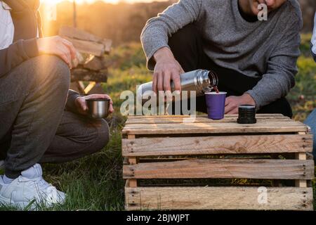 Gros plan portrait de jeune homme dans des vêtements décontractés qui versent du thé chaud de thermos à la jeune femme Banque D'Images