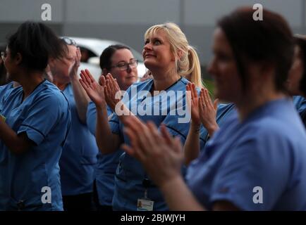 Les infirmières se sont accrochez à leurs collègues alors qu'elles regardent d'une fenêtre à l'hôpital universitaire Queen Elizabeth de Glasgow alors qu'elles se joignent aux applaudissements pour saluer les héros locaux au cours du Clap national de jeudi pour que les soignants reconnaissent et soutiennent les travailleurs et les soignants du NHS qui luttent contre la pandémie de coronavirus. Banque D'Images