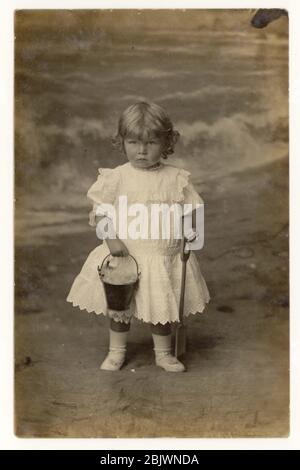 Début des années 1900 carte postale de bord de mer de jeune enfant (prob. Garçon) tenant un seau et une bêche, Eastbourne, Sussex, Angleterre Royaume-Uni vers 1907 Banque D'Images