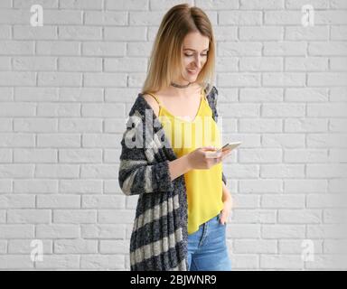 Jeune femme dans un gilet rayé sur fond de mur de briques Banque D'Images