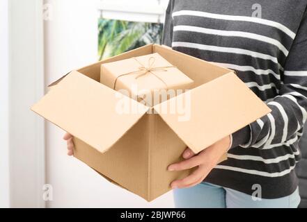 Femme tenant un colis avec boîte cadeau à la maison Banque D'Images