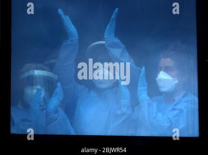 Le personnel infirmier se félicite en quelques minutes de la fenêtre de l'hôpital universitaire Queen Elizabeth de Glasgow, alors qu'il se joint aux applaudissements pour saluer les héros locaux du Clap national de jeudi pour que les soignants reconnaissent et soutiennent les travailleurs et les soignants du NHS qui luttent contre la pandémie de coronavirus. Banque D'Images