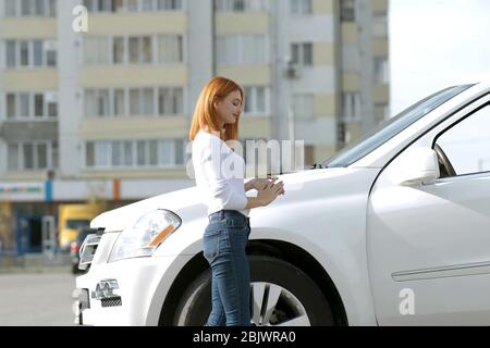 Yong jolie femme debout près d'une grande voiture tout terrain à l'extérieur. Fille du pilote dans les tenues de l'extérieur de son véhicule. Banque D'Images