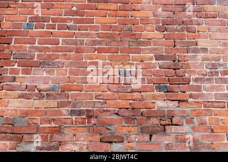 Un vieux mur de briques rouges avec plusieurs parties de la maçonnerie montrant leur âge, dommages et remplacement par des briques mal appariées crée une texture unique an Banque D'Images