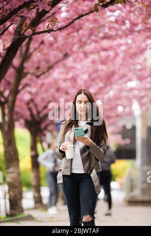 La beauté et la mode pour femmes. Style de vie urbain. Fille sur le fond des arbres à fleurs roses. Gros plan portrait de fille au printemps. Banque D'Images