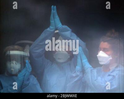 Le personnel infirmier se félicite en quelques minutes de la fenêtre de l'hôpital universitaire Queen Elizabeth de Glasgow, alors qu'il se joint aux applaudissements pour saluer les héros locaux du Clap national de jeudi pour que les soignants reconnaissent et soutiennent les travailleurs et les soignants du NHS qui luttent contre la pandémie de coronavirus. Banque D'Images