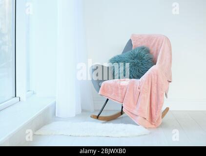 Oreiller et plaid moelleux sur fauteuil dans la chambre Banque D'Images